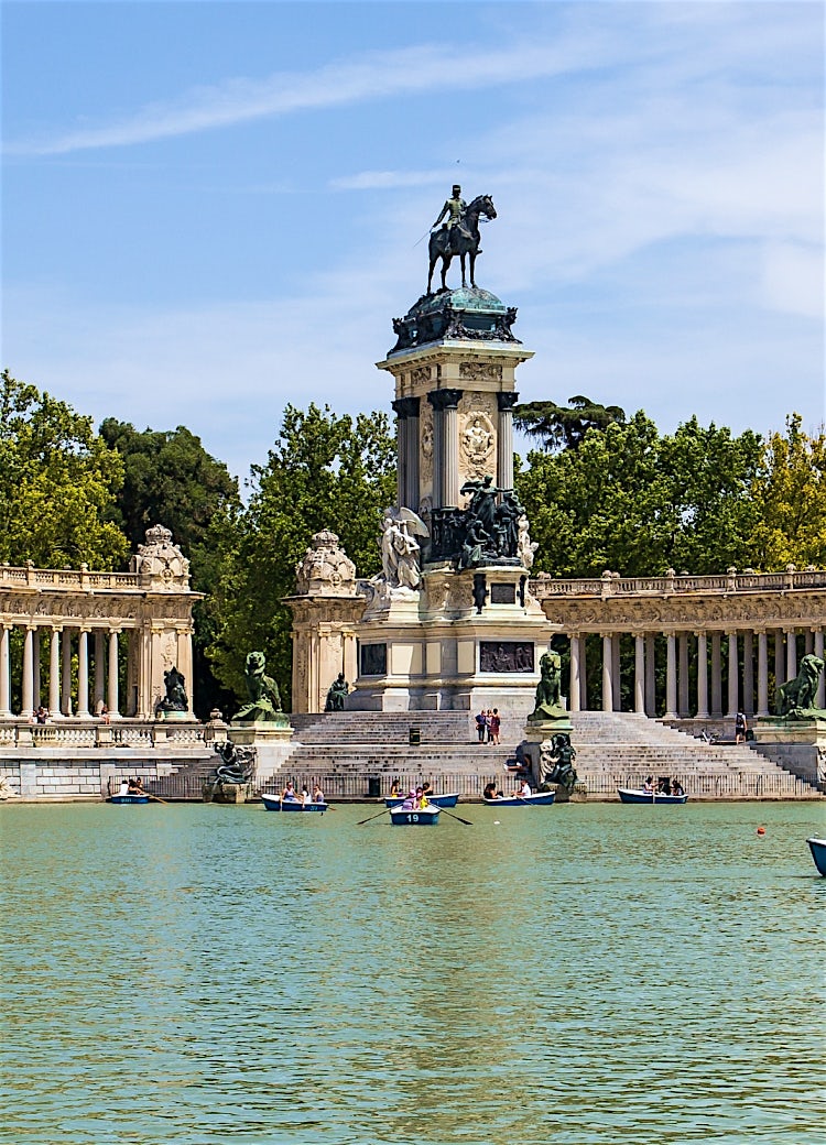 Monument to Alfonso XII in El Retiro Park, Madrid, Spain, featuring the iconic colonnade, lakeside setting, historic sculptures and rowing boats.