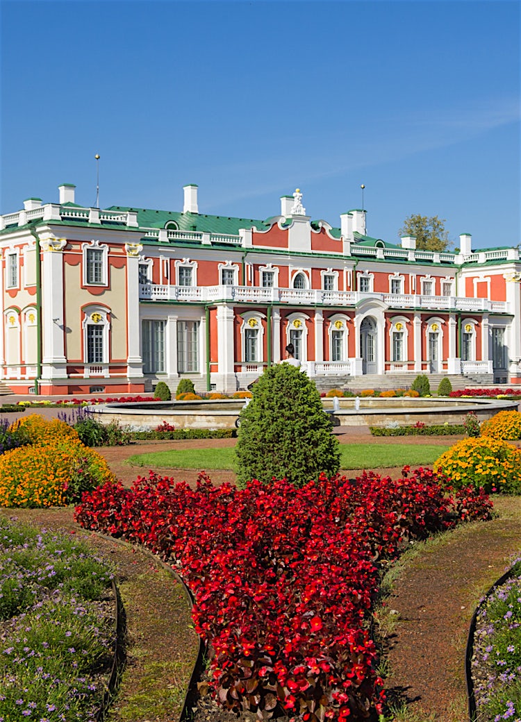 Kadriorg Palace in Tallinn, Estonia, with formal gardens, colorful flower beds, and elegant Baroque architecture under a clear blue sky.