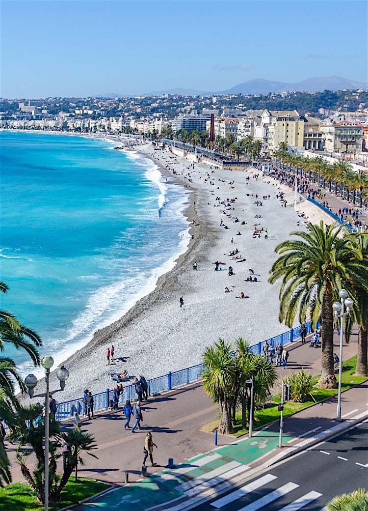 Nice Promenade des Anglais, France, with turquoise Mediterranean waters, palm-lined seafront, and the iconic French Riviera coastline.