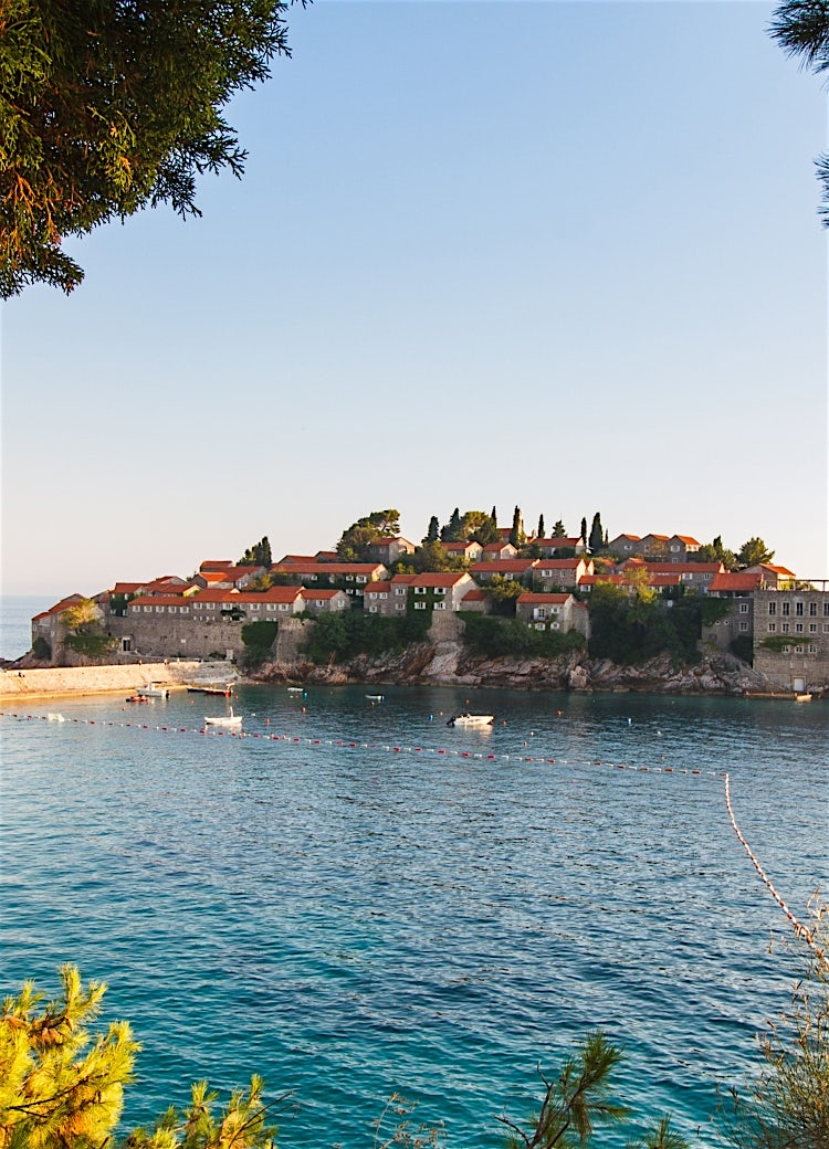 View of Sveti Stefan, Montenegro, featuring a historic stone islet village with red-roofed buildings overlooking the Adriatic Sea.