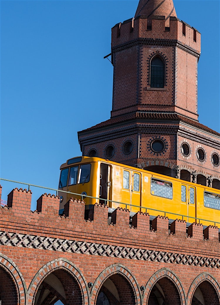 Berlin Oberbaum Bridge with iconic yellow U-Bahn train crossing historic red-brick towers in Germany.