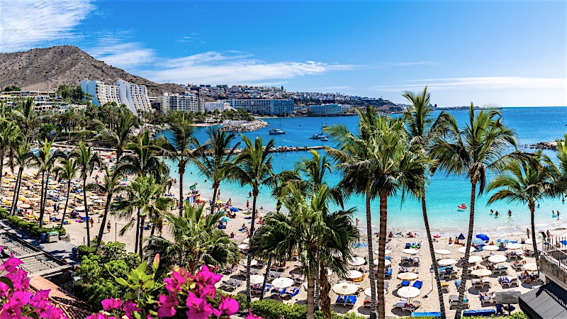 Gran Canaria beach resort with palm trees, golden sands, turquoise bay, beachfront hotels and vibrant Atlantic coastline views.
