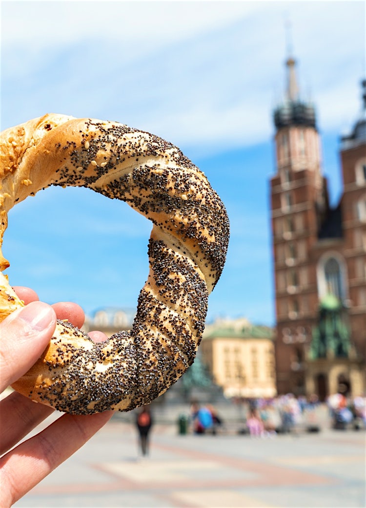 Kraków pretzel in Market Square with St. Mary’s Basilica backdrop, showcasing traditional Polish street food and historic architecture.