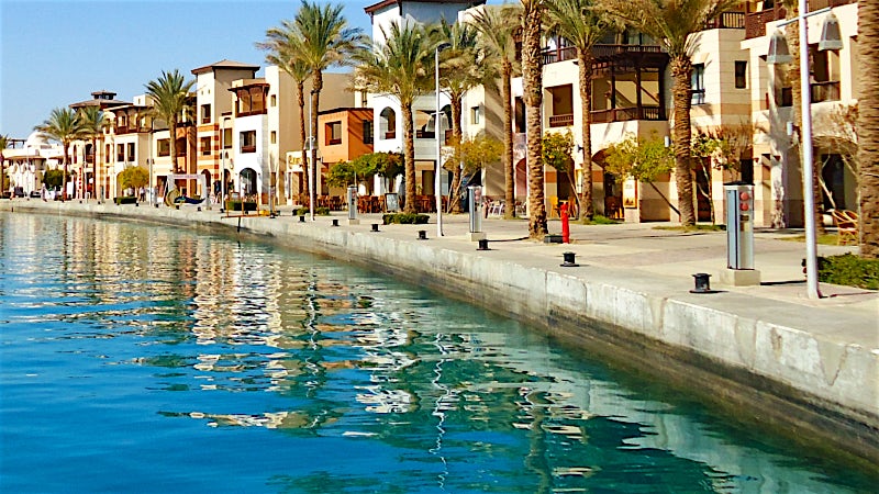 Marsa Alam Egypt waterfront promenade with palm trees, resort architecture and Red Sea views