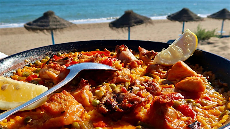 Large dish of Pealla on a table with the sea/beach in the background