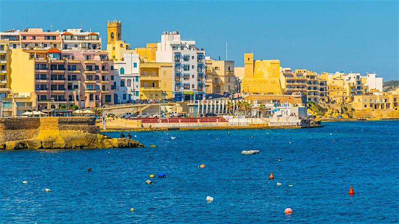 Bugibba Malta seafront with coastal promenade, Mediterranean waters and resort town skyline
