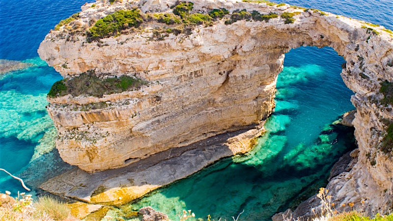 Tripitos Arch sea cave with turquoise waters and dramatic limestone cliffs, Paxos, Greece.