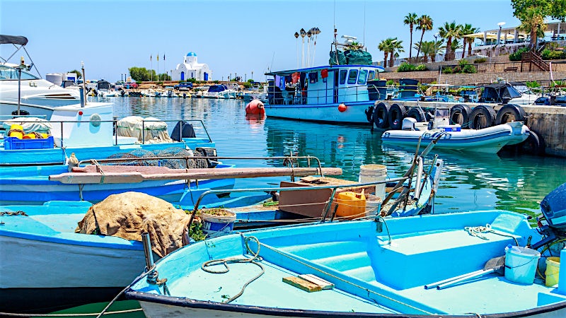 Protaras fishing harbour with colourful boats and Agios Nikolaos Chapel, Cyprus.