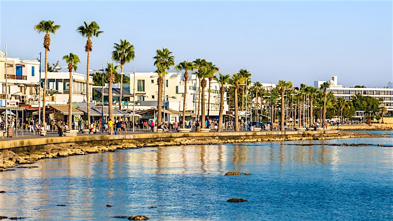 Paphos seafront promenade with palm trees, waterfront cafés and Mediterranean coastline, Cyprus.