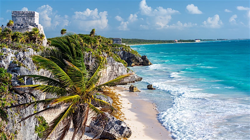 Tulum Mayan ruins overlooking turquoise Caribbean Sea and white sand coastline, Mexico.