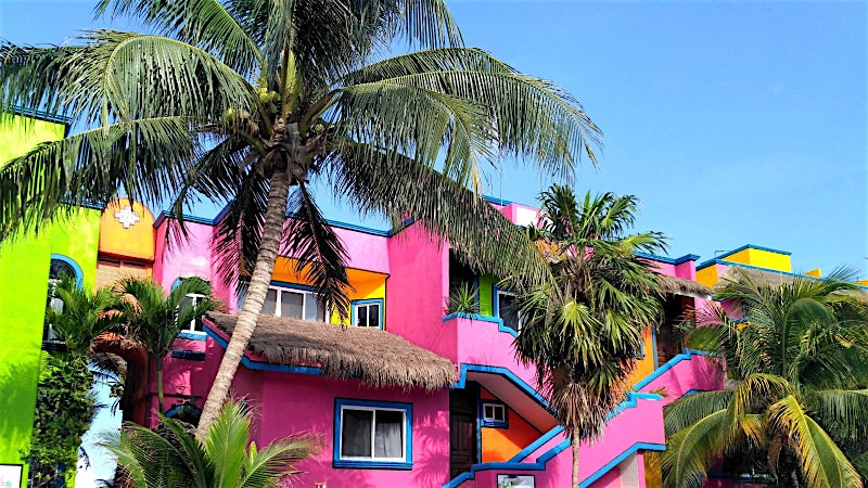 Colourful tropical resort with palm trees and vibrant Caribbean-style architecture, Riviera Maya, Mexico.