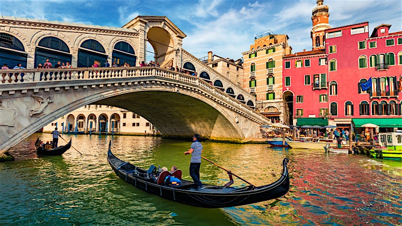 Venice Italy Rialto Bridge with gondolas, Grand Canal and colourful historic waterfront buildings