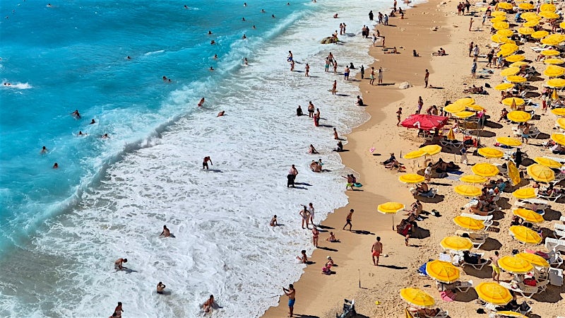Turkey beach with turquoise sea, golden sand, swimmers and Mediterranean coastline