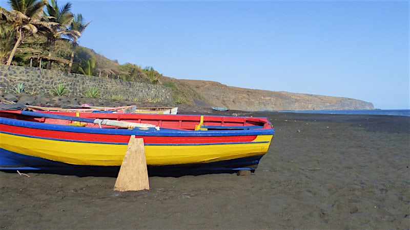 Colourful fishing boats on a black sand beach in São Filipe, Cape Verde coastline.