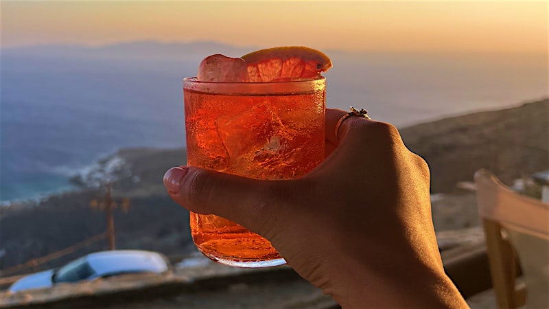 Sunset cocktail overlooking the Greek coastline from a scenic hillside bar.