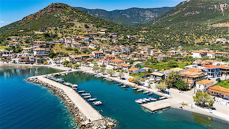 Aerial view of Glyfada harbour with turquoise waters, boats and a traditional Greek coastal village.