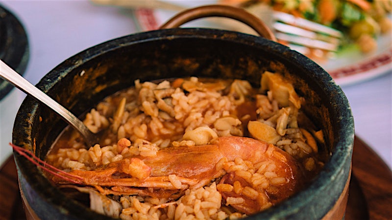 Traditional Cape Verde cachupa stew with rice, beans and meat served in a rustic pot.
