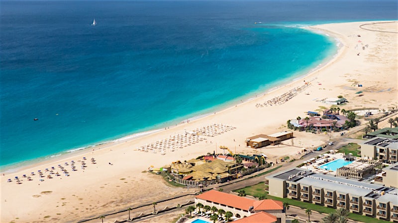 Aerial view of Santa Maria Beach with white sand, turquoise waters and beachfront resorts in Cape Verde.