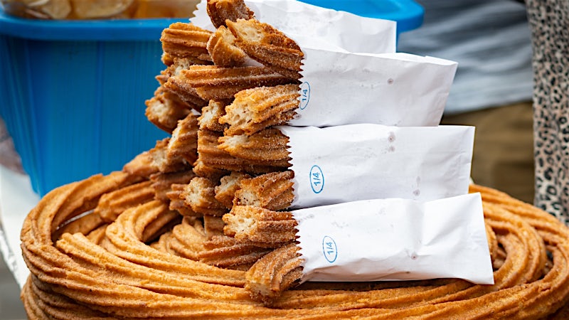 Freshly made Mexican churros coated in cinnamon sugar at a traditional market stall.