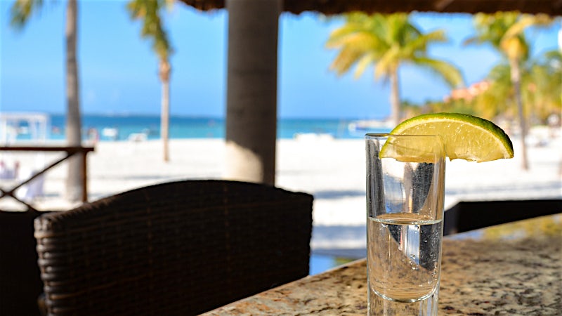 Shot of Mexican tequila with lime served at a beachfront bar overlooking the Caribbean Sea.