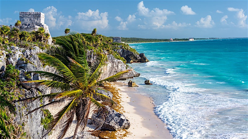 Tulum Mayan ruins overlooking a white sand beach and turquoise Caribbean Sea in Mexico.