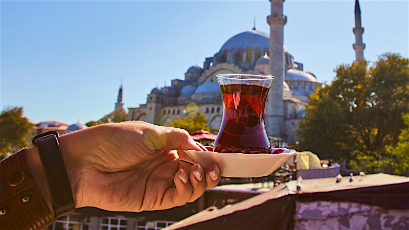 Traditional Turkish tea served with historic mosque backdrop in Istanbul, Turkey.