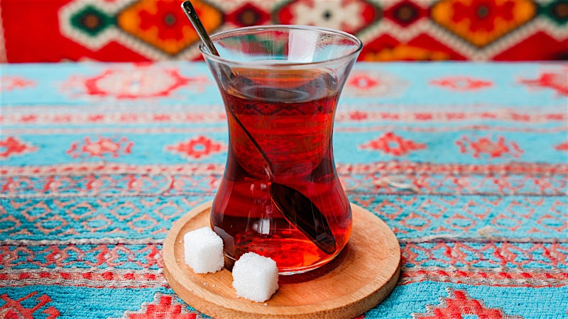 Traditional Turkish tea served in a glass on a patterned table setting.
