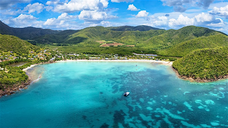 Aerial view of Antigua’s turquoise bay, white-sand beach and lush Caribbean coastline.
