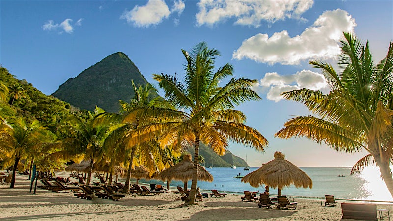 Palm-lined beach with Pitons mountain view in St Lucia, Caribbean.