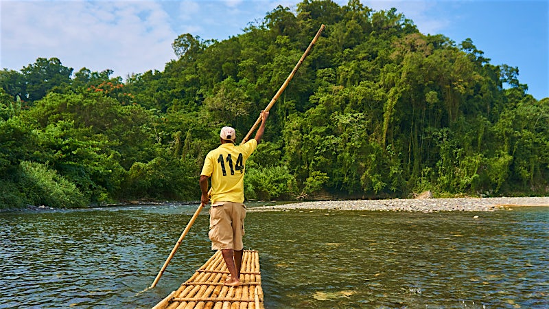 Traditional bamboo rafting on a lush tropical river in Jamaica.