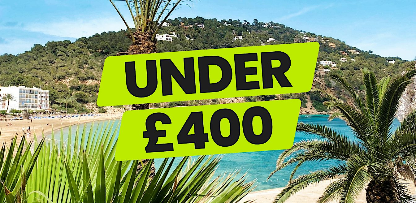 Palm-fringed bay with turquoise water and hillside coast, highlighting Value holidays and sunny beach breaks available for under £400.