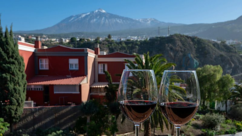 Two glasses of red wine overlook a Tenerife hillside with Mount Teide in the distance, capturing relaxed Value holidays in the Canary Islands.