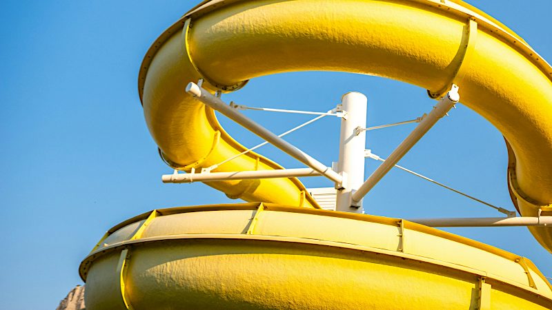 Bright yellow water slide twists against a clear blue sky, showcasing family fun and adventure on Tenerife Value holidays.
