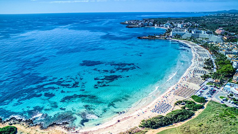 Sa Coma beach with crystal-clear sea, golden sand and Mallorca coastal resorts.