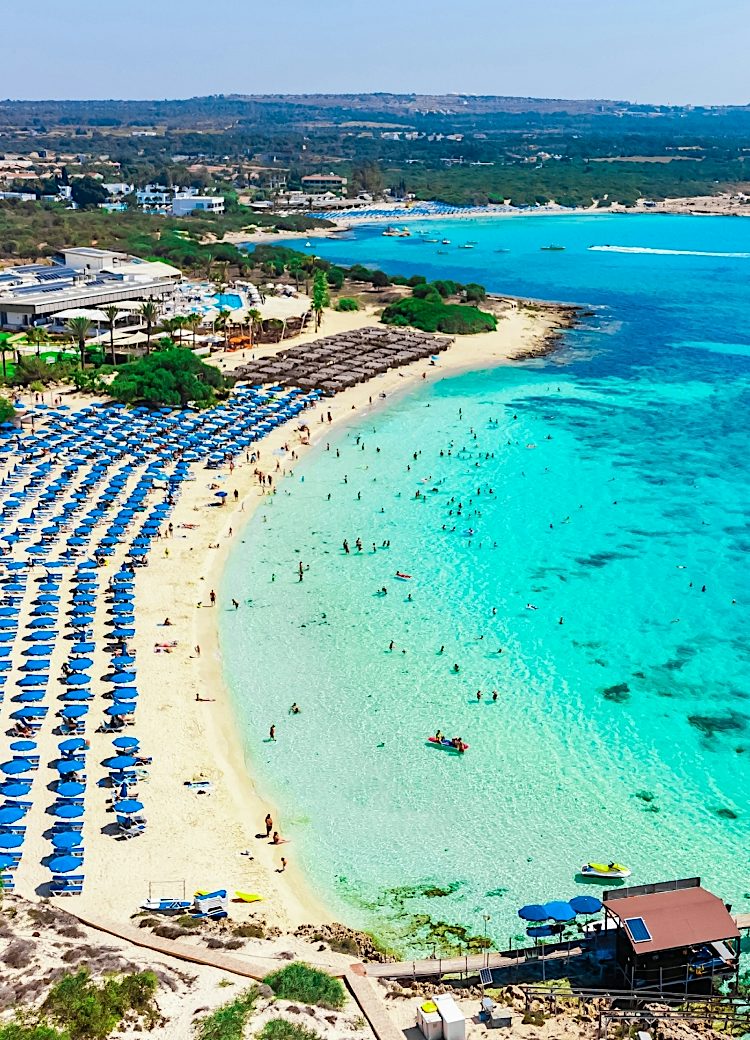 Aerial view of Ayia Napa beach in Cyprus with turquoise sea, sun loungers and beachfront resort, perfect for bright Value holidays.